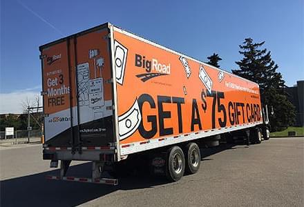 Semi truckside advertising with orange ads for Big Road saying "Get three months free" and "Get a $75 gift card."
