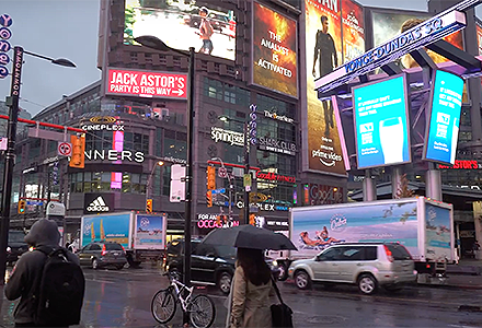 Billboard advertisements on mobile trucks for Travel Cuba driving past Yonge and Dundas Square in Toronto