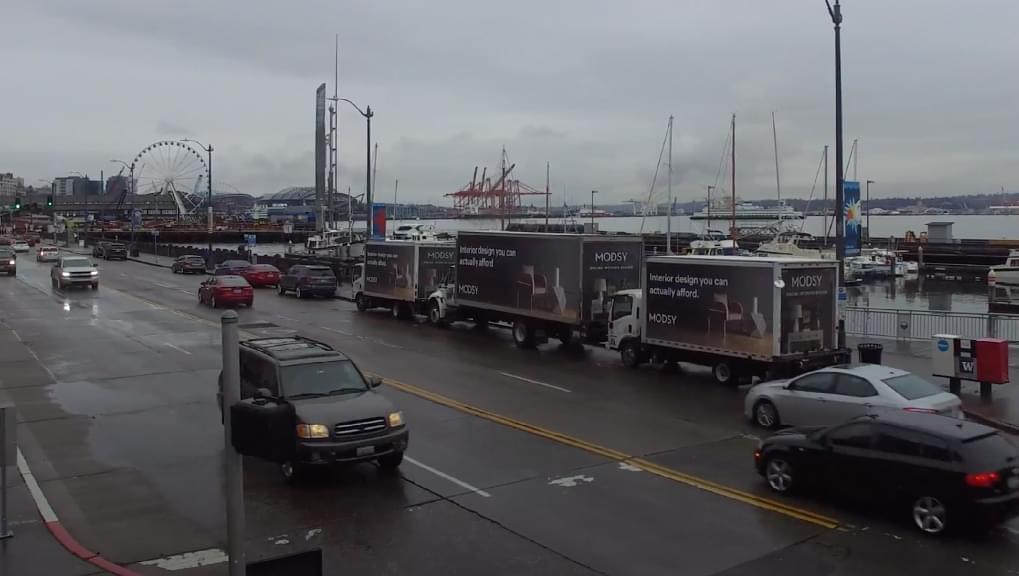 Three Mobile Billboards for Modsy parked on the waterfront by Pike Place Fish Market