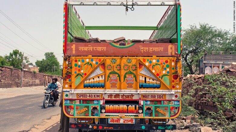 An image of th eback of a truck that is colourfully painted with symbols. 