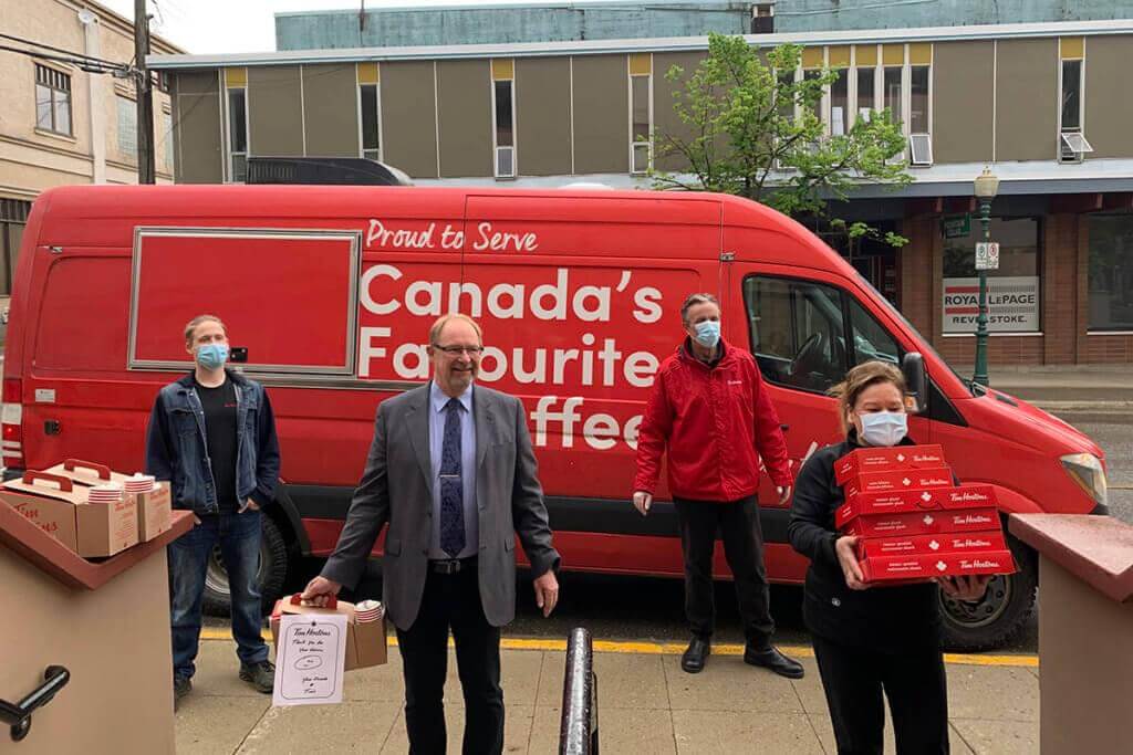 An image of four Tim Hortons employees delivering coffee and doughnuts to health care workers. 