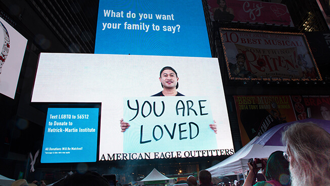 A massive DOOH billboard by American Eagle Outfitters and Hetrick-Martin Institute. With people from the LGBTQ community holding signs.