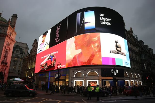 An image of a street corner full of digital OOH billboards. They're all displaying different ads.