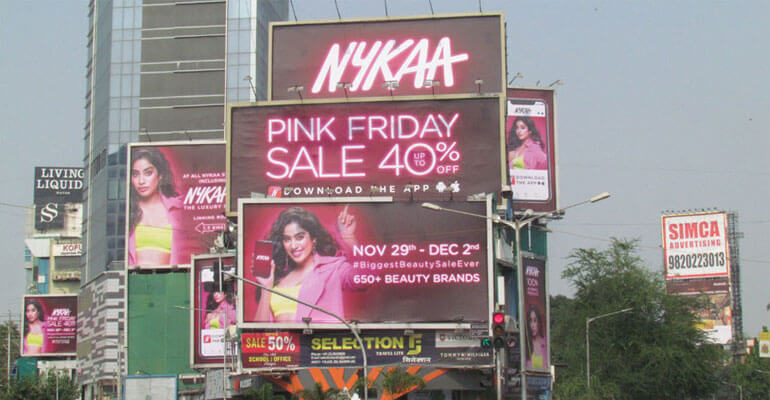 An image of a bunch of large billboard ads for Nykaa. All the ads are grouped together and promote their Black Friday sales in bright pink florescent lettering.