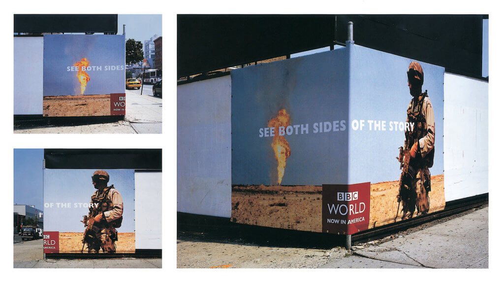 Images of a billboard at the intersection of two buildings that wraps around the corning of one that shows two different sides to one story. The BBC ad shows an explosion on one side and a soldier carrying a gun in the other.