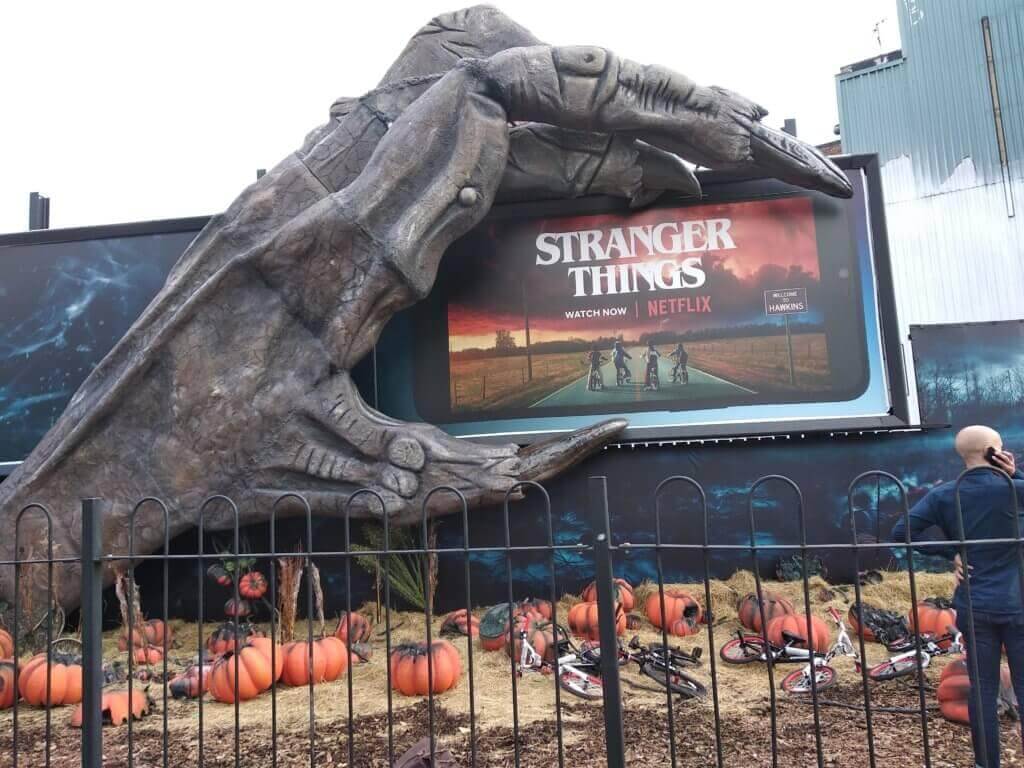 Billboard for Netflix's Strnger Things. A monstrous hand is holding a billboard that looks like a phone. 