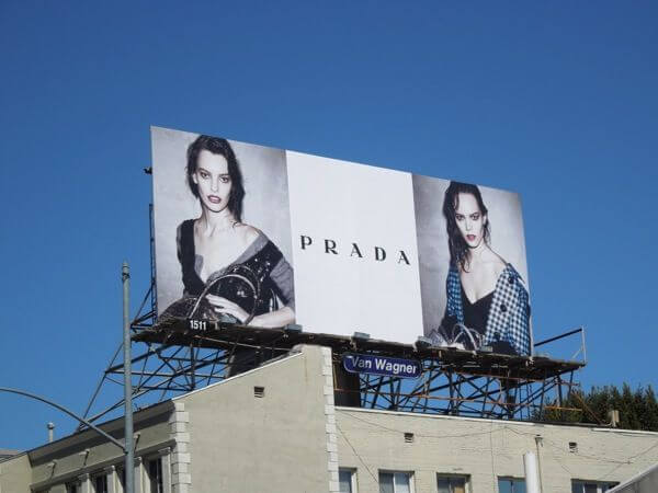 An image of a large billboard for Prada. The billboard has two models, one on each side.