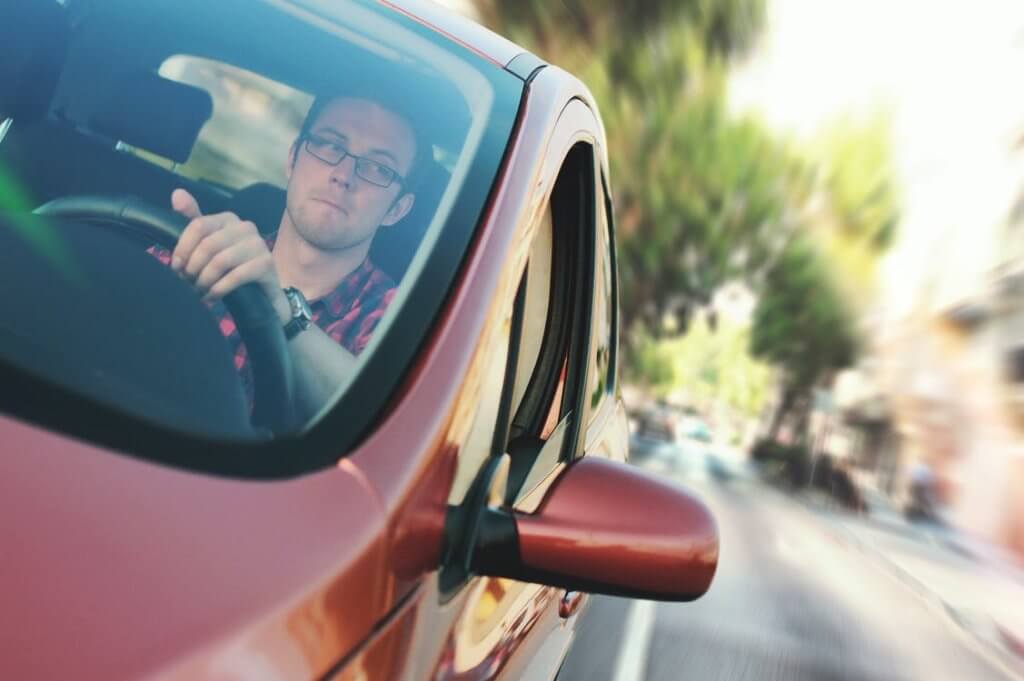 An image of a man driving and looking to his left.