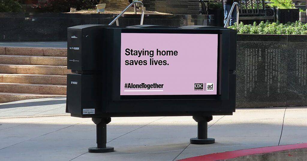 An image of a ad on the street about staying home to slow the spread of COVID-19.