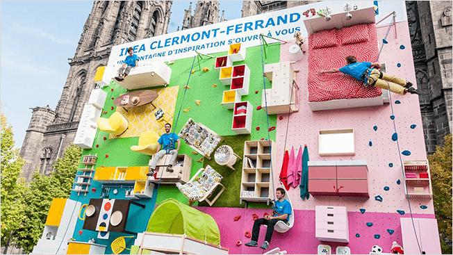 An image of an interactive ad by IKEA. The ad is a rock climbing wall with furniture placed all over it.