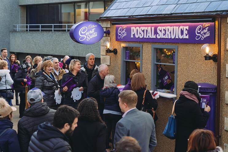An image of a bunch of people lined up outside of a Cadbury postal service pop-up.