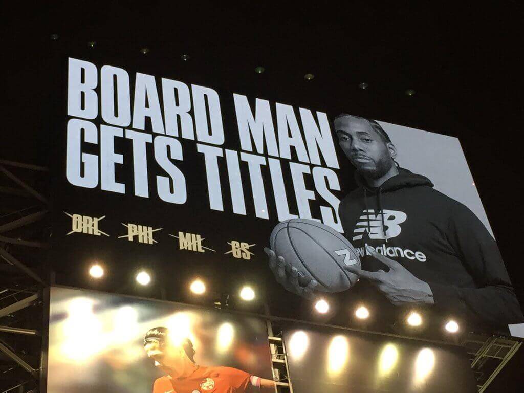 An image of an advertisement for New Balance. It has Kawhi Leonard pointing to a basketball and big, bold letters that say "Board man gets titles". 