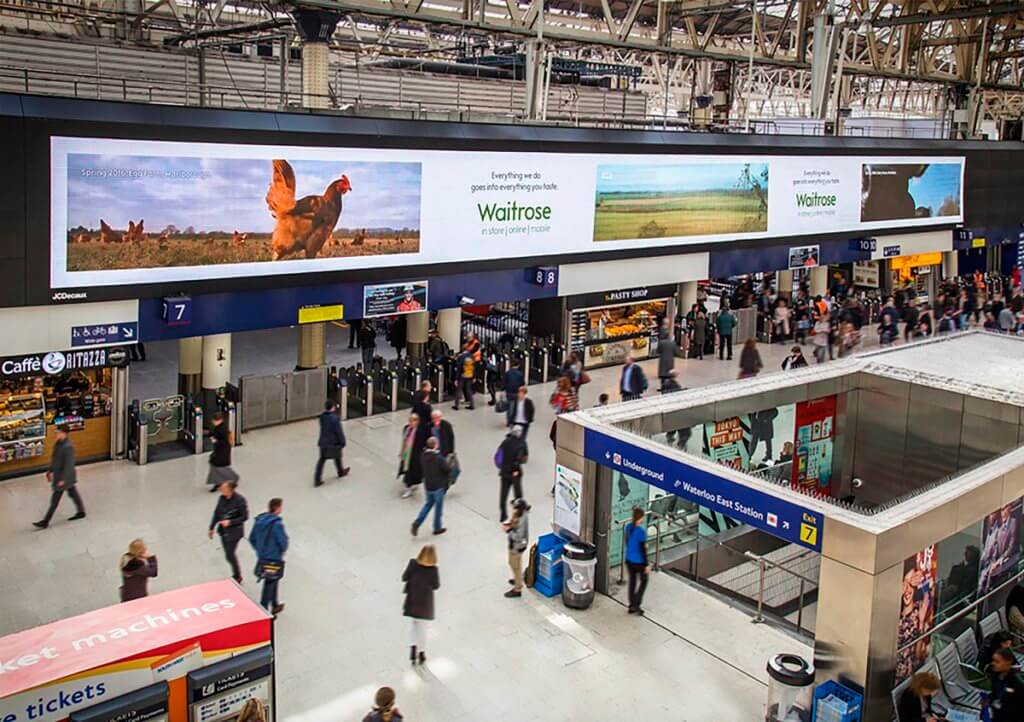 An image of a busy airport that has a large DOOH billboard at for Waitrose. It shows live video of Waitrose's farms.