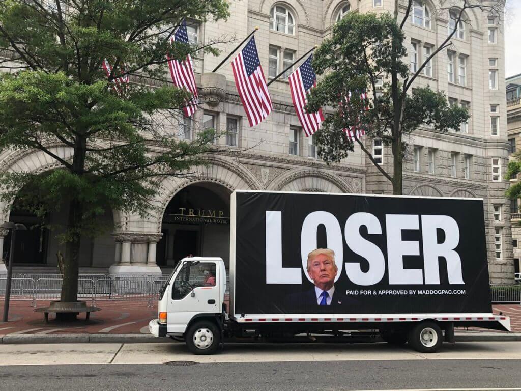 An image of a mobile ad that calls Trump a loser with an image of Trump on it. Truck sits in front of one of Trump's towers.