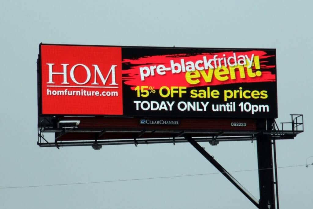 An image of a large billboard for homfurniture.com. The ad is black, red, and yellow with large bold lettering.