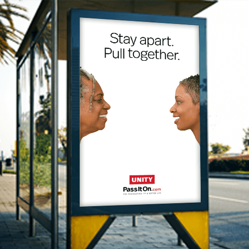 An image of a bus-stop advertisement. The ad is for Unity and says "Stay apart. Pull together." and has two women standing apart and smiling at each other.