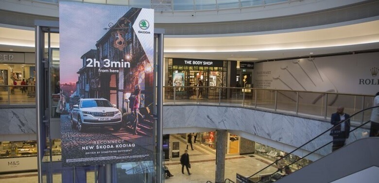 A DOOH ad at an airport for Skoda displaying a Skoda car and the time it takes to get to Paris.