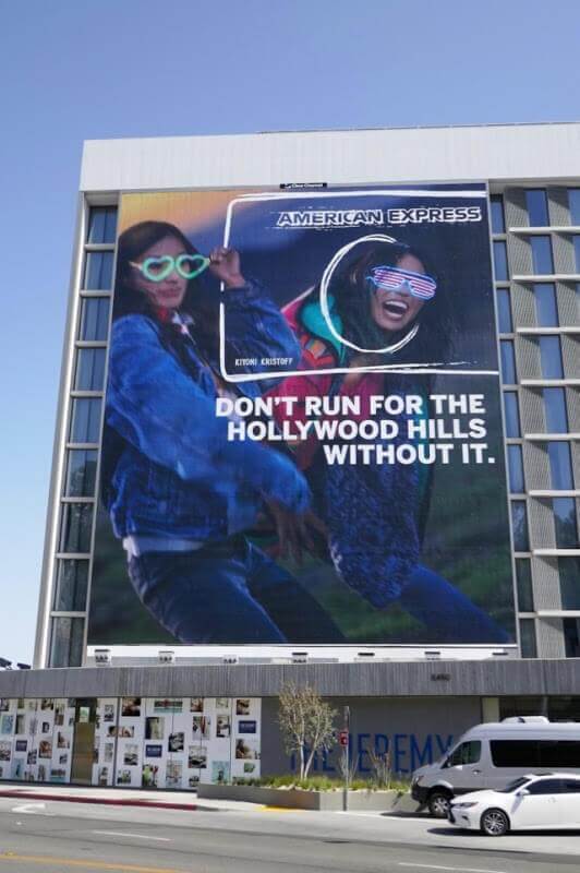 Picture of American Express billboard on the side of a building. Ad reads, "Don't run for the Hollywood Hills without it."