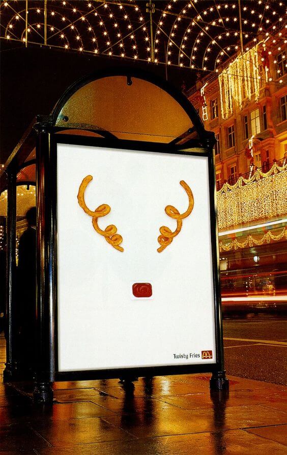 An image of a bus stop ad for McDonald's. The ad shows two curly fries and a ketchup package that work together to look like a reindeer. 