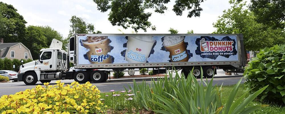 An image of a truck with an advertisement on it for Dunkin' Donuts coffee. 