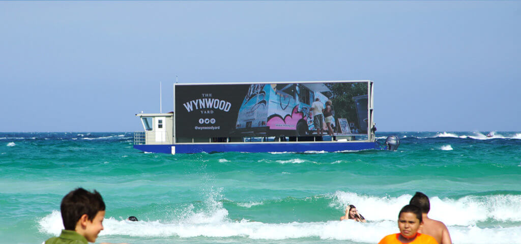 Billboard on boat advertising Wynwood near the shoreline of Miami Beach.