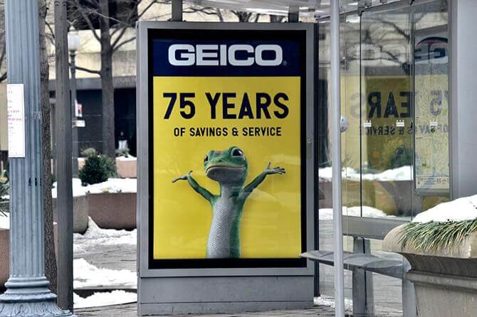 Photo of Geico's bus shelter advertisement celebrating their 75th brand anniversary. Advertisement says "75 years of savings & service"