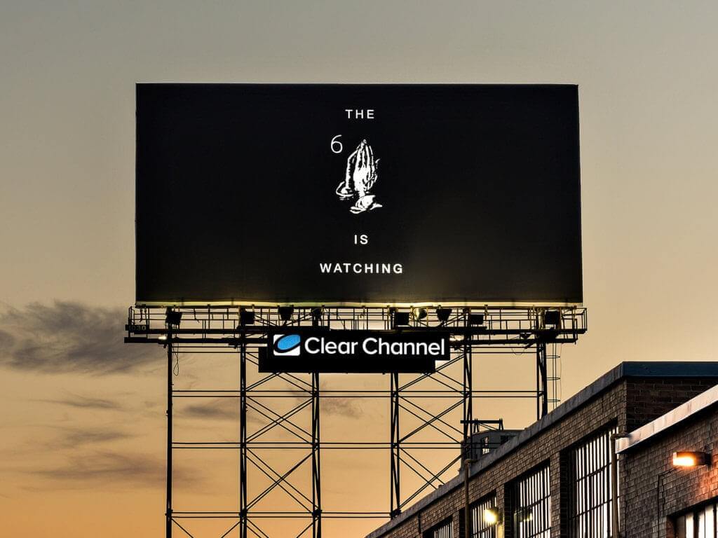 An image of a black and white billboard that says, "The 6 is watching". It also has praying hands in the middle.