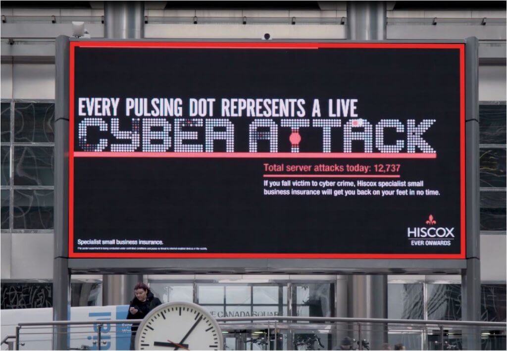 A DOOH billboard ad for Cyberattacks. As the cyberattacks occur, red dots on the lettering grow bigger.