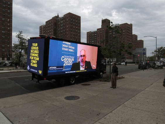 A truck with an operational digital billboard on its side showing the US Census 2020 news. 