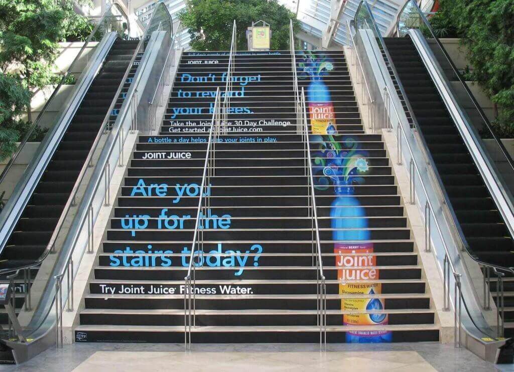 Photo of Join Juice Fitness Water out-of-home advertisement on a flight of stairs.