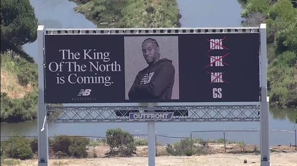 Billboard from New Balance in partnership with Kawhi Leonard. Ad reads, "The King of the North is coming." and crosses off the cities, Orlando, Philadelphia, and Milwaukee. 