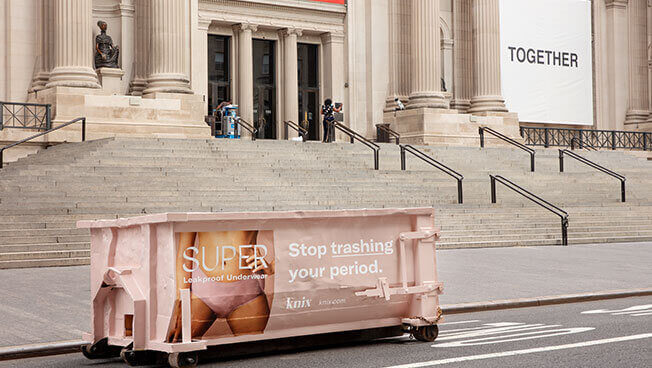 An image of a dumpster truck ad for Knix placed in front of the MET in NYC.