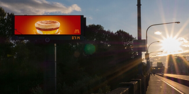 An image of the rising sun next to a billboard for a McDonald's McMuffin.