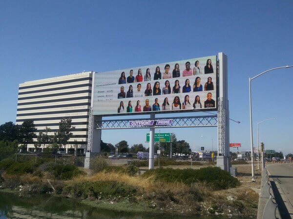 Billboard of #ilooklikeanengineer facebook portraits on highway.