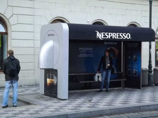 An image of a bus-stop advertisement for Nespresso. The bus-stop is dressed up as the side of a Nespresso machine.