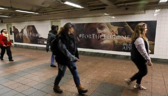 Image of subway commuters walking by Game of Thrones OOH wallscape in subway station.