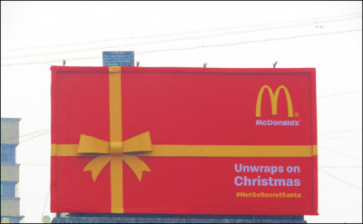 An image of a billboard with an ad on it for McDonald's. The billboard looks like it's wrapped like a gift with the classic McDonald's colours of red and yellow.