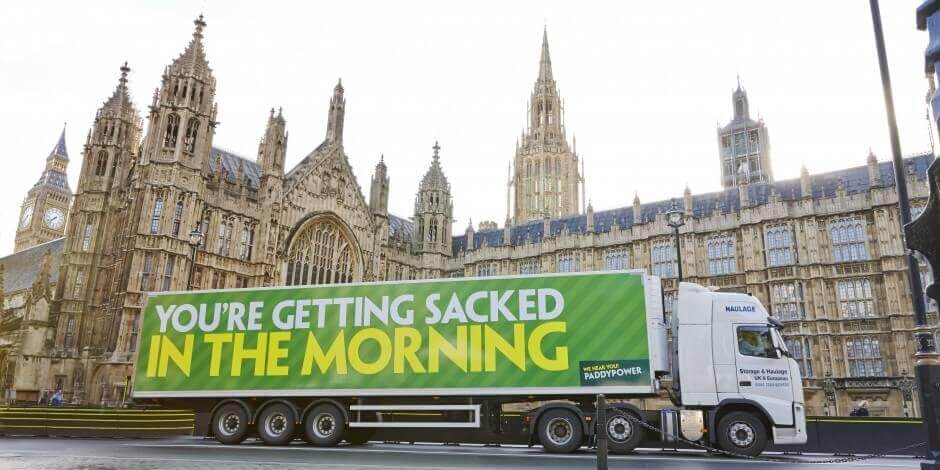 An image of a truck in front of parliament. The truck has an ad for Paddy Power that says, "You're getting sacked in the morning". 