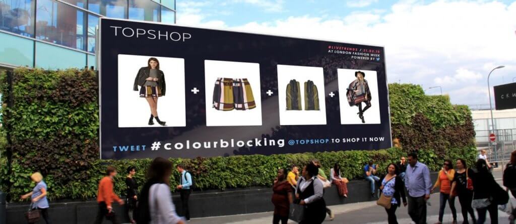 A billboard ad for Topshop with people passing by.