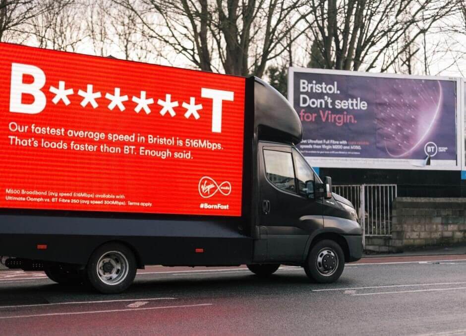 An image of a truck-side ad for Virgin Mobile that says, "B******T our fastest average speed in Bristol is 516Mbps. That's loads faster than BT. Enough said.". Also has a BT ad in the background on a billboard.
