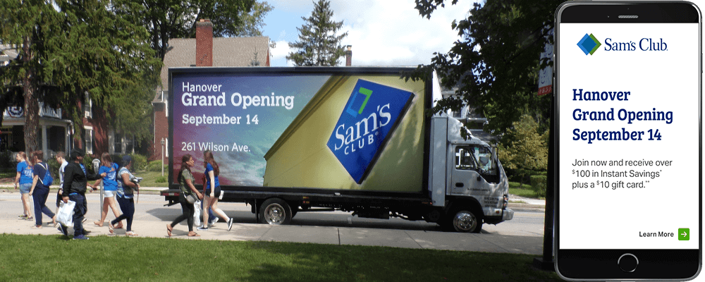 An image of a truck-side ad for the grand opening of Sam's Club. Also shows the same ad on an Iphone.