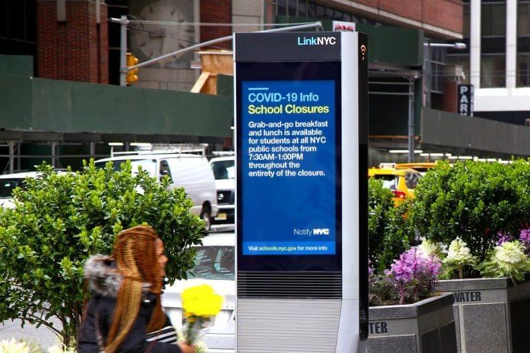 An image of a digital billboard on the street that updates by itself depending on the news. In this image it is providing passersby with the news about school closures.