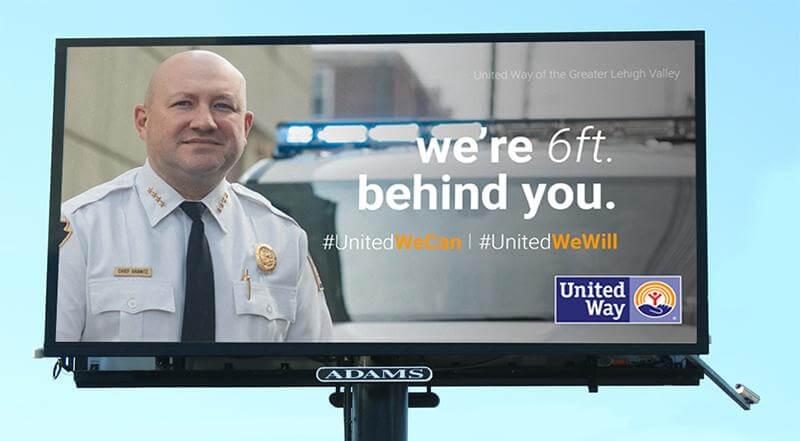 United Way billboard with a man on one side and copy that says, "We're 6 feet behind you."
